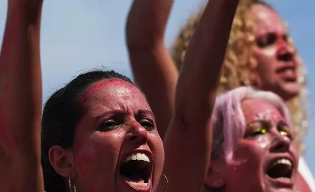 Women protest femicide following a series of high-profile cases in the country, on Copacabana beach, Rio de Janeiro, Sunday, Dec. 7, 2025. (AP Photo/Silvia Izquierdo)