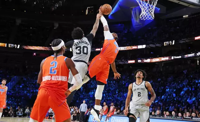 Oklahoma City Thunder guard Luguentz Dort (5) jumps to the basket near San Antonio Spurs forward Julian Champagnie (30) during the first half of an NBA Cup semifinals basketball game, Saturday, Dec. 13, 2025, in Las Vegas. (AP Photo/Ronda Churchill)