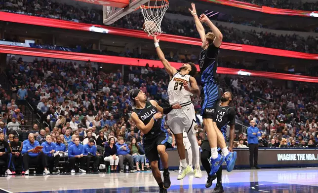 Denver Nuggets guard Jamal Murray (27) makes a move to the basket between guard Ryan Nembhard (9) and Dallas Mavericks forward Cooper Flagg (32) during the first quarter of an NBA basketball game Tuesday, Dec. 23, 2025, in Dallas. (AP Photo/Sam Hodde)