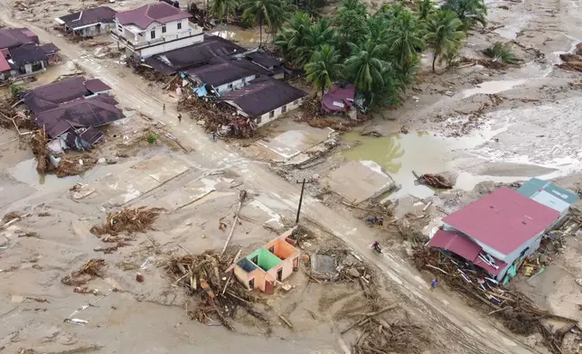 In this aerial photo taken using a drone, people are seen making their way on a muddy road at a village affected by a flash flood in Batang Toru, North Sumatra, Indonesia, Tuesday, Dec. 2, 2025. (AP Photo/Binsar Bakkara)