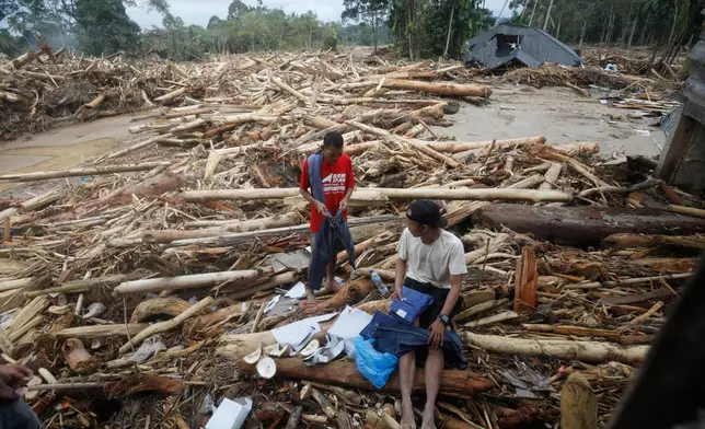 Survivors inspect clothings they salvaged at a village affected by a flash flood in Batang Toru, North Sumatra, Indonesia, Tuesday, Dec. 2, 2025. (AP Photo/Binsar Bakkara)
