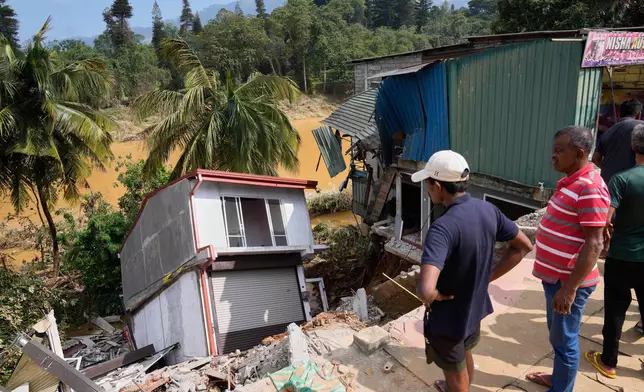 People look at a building damaged by the floods in Peradeniya, Sri Lanka, Monday, Dec. 1,2025. (AP Photo/Eranga Jayawardena)