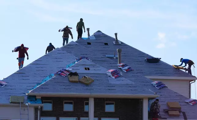 Roofers work atop a house in Anna, Texas, Thursday, Dec. 18, 2025. (AP Photo/LM Otero)