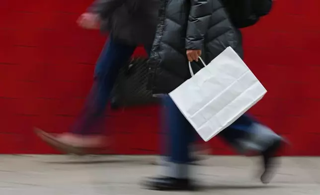 FILE - A person carries a shopping bag in Philadelphia, Wednesday, Dec. 10, 2025. (AP Photo/Matt Rourke, File)