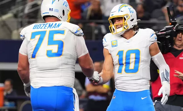 Los Angeles Chargers quarterback Justin Herbert (10) celebrates his touchdown with center Bradley Bozeman (75) during the first half of an NFL football game against the Dallas Cowboys, Sunday, Dec. 21, 2025, in Arlington, Texas. (AP Photo/Tony Gutierrez)