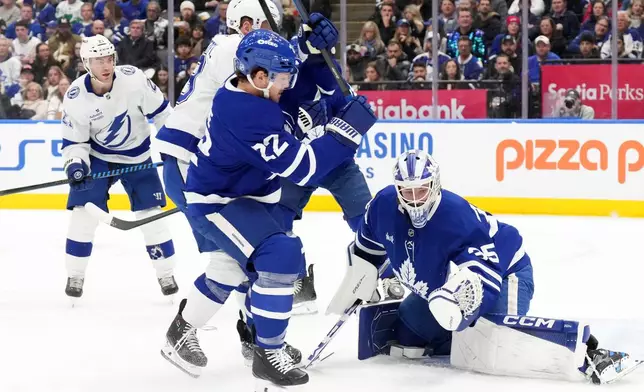 Toronto Maple Leafs goaltender Dennis Hildeby (35) makes a save in front of Tampa Bay Lightning's Jake Guentzel (59) and Leafs defenseman Jake McCabe (22) during the first period of an NHL hockey game in Toronto, Monday, Dec. 8, 2025. (Chris Young/The Canadian Press via AP)