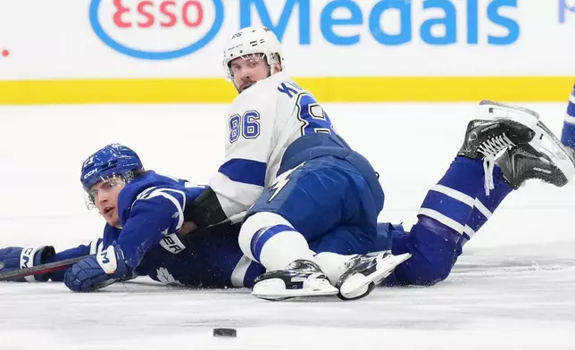 Toronto Maple Leafs left wing Matthew Knies (23) battles for the puck with Tampa Bay Lightning right wing Nikita Kucherov (86) during the second period of an NHL hockey game in Toronto, Monday, Dec. 8, 2025. (Chris Young/The Canadian Press via AP)