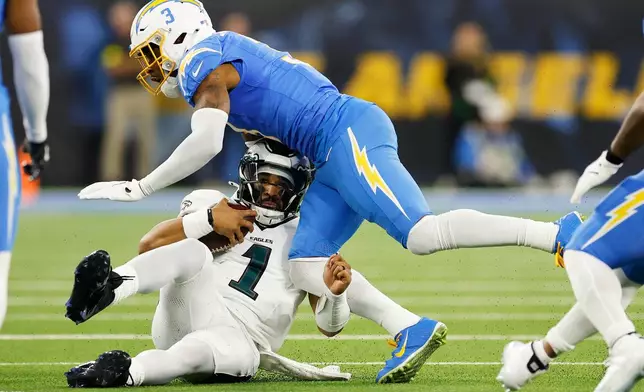 Philadelphia Eagles quarterback Jalen Hurts (1) slides under Los Angeles Chargers free safety Derwin James (3) during the first half of an NFL football game Monday, Dec. 8, 2025, in Inglewood, Calif. (AP Photo/Caroline Brehman)