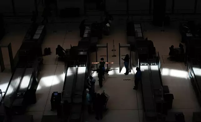A traveler holds their arms out at a security point at Tocumen International Airport in Panama City, Thursday, Dec. 4, 2025, as Copa Airlines temporarily suspends flights to and from Caracas due to pilots reporting intermittent navigation signal issues. (AP Photo/Matias Delacroix)