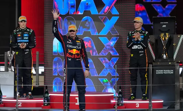 Red Bull driver Max Verstappen of the Netherlands waves towards the crowd on the podium after the Formula One Abu Dhabi Grand Prix at the Yas Marina Circuit in Abu Dhabi, UAE, Sunday, Dec. 7, 2025. (AP Photo/Altaf Qadri)