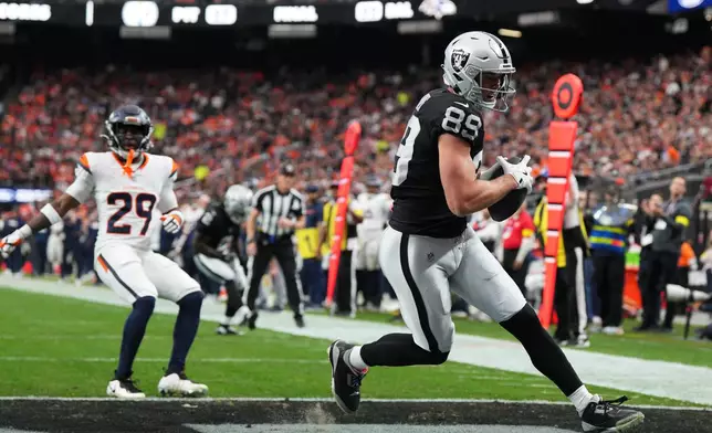 Las Vegas Raiders tight end Brock Bowers (89) scores in front of Denver Broncos cornerback Ja'Quan McMillian (29) during the first half of an NFL football game in Las Vegas, Sunday, Dec. 7, 2025. (AP Photo/Candice Ward)