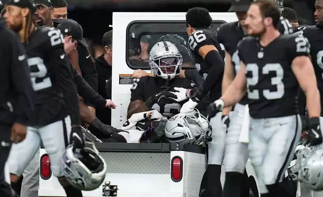 Las Vegas Raiders cornerback Kyu Blu Kelly, middle, is carted off the field during the first half of an NFL football game against the Denver Broncos in Las Vegas, Sunday, Dec. 7, 2025. (AP Photo/Gregory Bull)