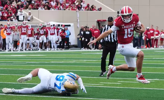 FILE - Indiana quarterback Fernando Mendoza (15) runs past UCLA defensive lineman Jacob Busic (97) during the first half of an NCAA college football game, Saturday, Oct. 25, 2025, in Bloomington, Ind. (AP Photo/Darron Cummings, File)