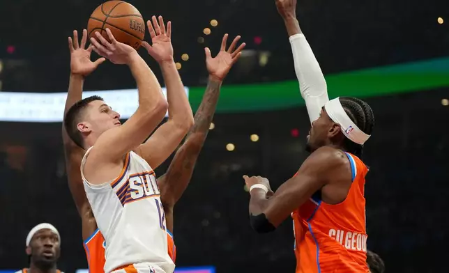 Phoenix Suns guard Collin Gillespie, left, shoots over Oklahoma City Thunder guard Shai Gilgeous-Alexander during the first half of an NBA Cup basketball game, Wednesday, Dec. 10, 2025, in Oklahoma City. (AP Photo/Kyle Phillips)