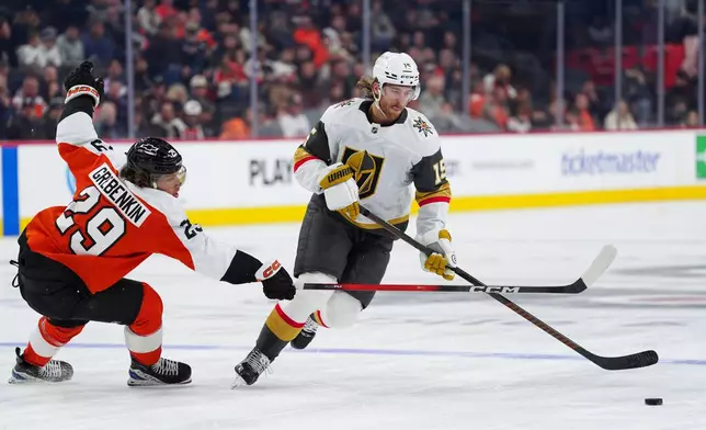 Vegas Golden Knights' Noah Hanifin, right, skates the puck past Philadelphia Flyers' Nikita Grebenkin during the first period of an NHL hockey game, Thursday, Dec. 11, 2025, in Philadelphia. (AP Photo/Derik Hamilton)