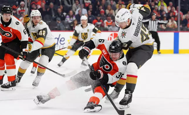 Philadelphia Flyers' Emil Andrae, center, is tripped by Vegas Golden Knights' Ivan Barbashev (49) during the first period of an NHL hockey game, Thursday, Dec. 11, 2025, in Philadelphia. (AP Photo/Derik Hamilton)