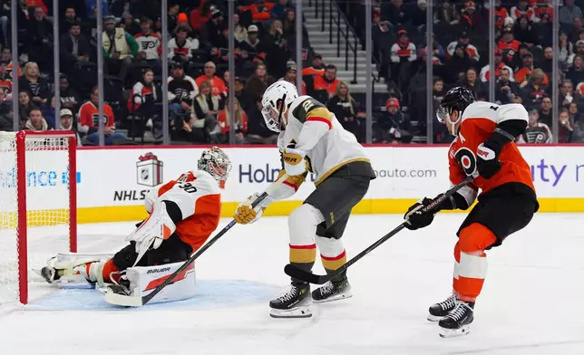 Vegas Golden Knights' Zach Whitecloud, center, scores a goal past Philadelphia Flyers goaltender Dan Vladar and Travis Konecny (11) during the first period of an NHL hockey game, Thursday, Dec. 11, 2025, in Philadelphia. (AP Photo/Derik Hamilton)