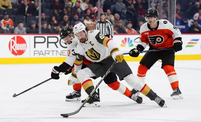 Vegas Golden Knights' Mark Stone, center skates the puck past Philadelphia Flyers' Emil Andrae (36) and Jamie Drysdale (9) during the third period of an NHL hockey game, Thursday, Dec. 11, 2025, in Philadelphia. (AP Photo/Derik Hamilton)