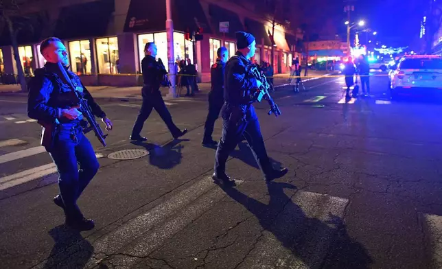 Law enforcement officials carry rifles while walking on a street in a neighborhood near Brown University in Providence, R.I., on Saturday, Dec. 13, 2025 during the investigation of a shooting. (AP Photo/Steven Senne)