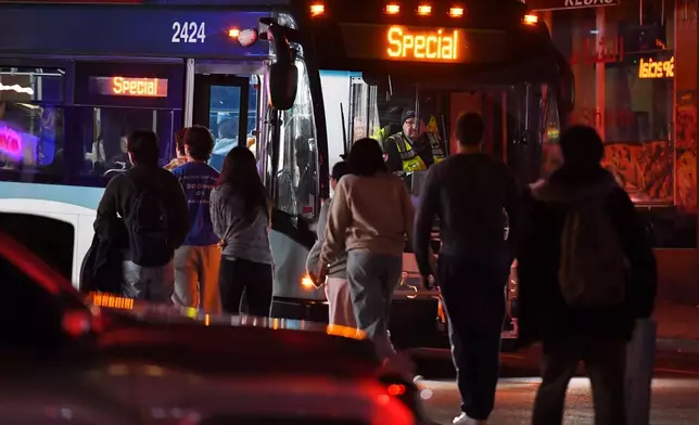 People board a bus in a neighborhood near Brown University, Saturday, Dec. 13, 2025, in Providence, R.I., during the investigation of a shooting. (AP Photo/Steven Senne)