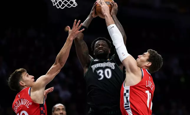 Minnesota Timberwolves forward Julius Randle, middle goes up for a shot as Los Angeles Clippers center Brook Lopez (11) and guard Bogdan Bogdanovic (10) defend during the first half of an NBA basketball game Saturday, Dec. 6, 2025, in Minneapolis. (AP Photo/Matt Krohn)