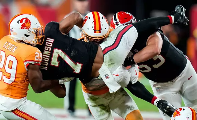Tampa Bay Buccaneers safety Christian Izien (29) hits Atlanta Falcons running back Bijan Robinson (7) during the first half of an NFL football game, Thursday, Dec. 11, 2025, in Tampa, Fla. (AP Photo/Chris O'Meara)