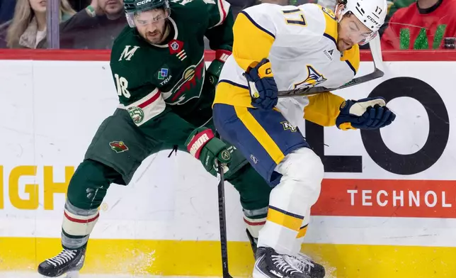 Minnesota Wild's Vinnie Hinostroza (18) and Nashville Predators Tyson Jost (17) battle for the puck in the second period of an NHL hockey game against the Minnesota Wild, Tuesday, Dec. 23, 2025, in St. Paul, Minn. (Carlos Gonzalez/Star Tribune via AP)