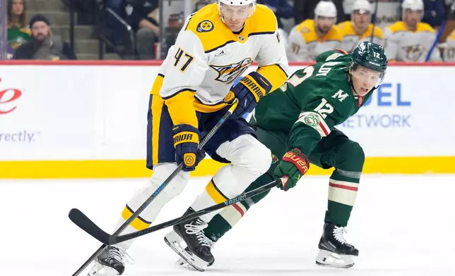 Nashville Predators' Michael McCarron (47) and Minnesota Wild's Matt Boldy (12) battle for the puck in the first period of an NHL hockey game against the Minnesota Wild, Tuesday, Dec. 23, 2025, in St. Paul, Minn. (Carlos Gonzalez/Star Tribune via AP)