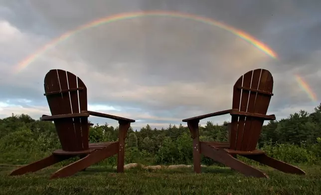 FILE - With two empty Adirondack chairs next to a fire pit, a rainbow stretches across the sky at Adams Pond in East Derry, N.H., Thursday July 1, 2010. (AP Photo/Charles Krupa, File)