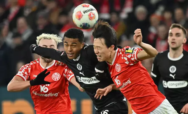 St. Pauli's Joel Chima Fujita, centre, Mainz's Jae-sung Lee and Mainz's Benedict Hollerbach, left, fight for the ball during the Bundesliga soccer match between FSV Mainz 05 and FC St. Pauli, in Mainz, Germany, Sunday Dec. 21, 2025. (Torsten Silz/dpa via AP)