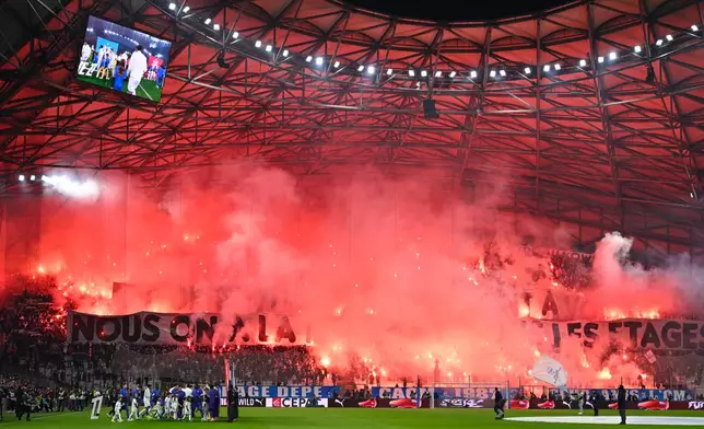 Fans light flares before the French League One soccer match between Marseille and Monaco in Marseille, France, Sunday, Dec. 14, 2025. (AP Photo/Philippe Magoni)