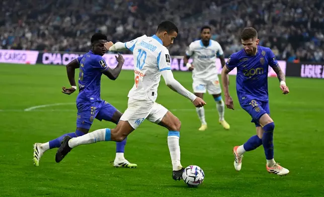 Marseille's Mason Greenwood, center, runs past to Monaco's Caio Henrique, right, during the French League One soccer match between Marseille and Monaco in Marseille, France, Sunday, Dec. 14, 2025. (AP Photo/Philippe Magoni)