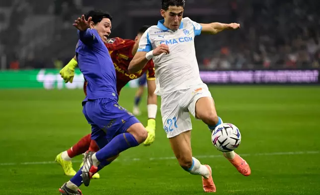 Marseille's Nayef Aguerd, right, challenges with Monaco's Takumi Minamino during the French League One soccer match between Marseille and Monaco in Marseille, France, Sunday, Dec. 14, 2025. (AP Photo/Philippe Magoni)