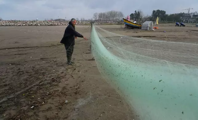 A fisherman prepares his net at the beach of the southern coast of the Caspian Sea outside the port city of Bandar Anzali, Iran, Tuesday, Dec. 23, 2025. (AP Photo/Vahid Salemi)