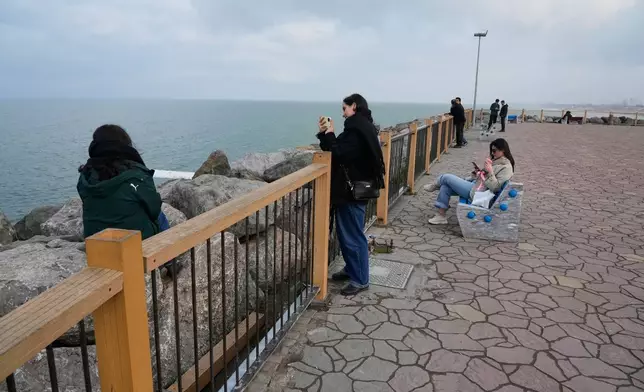 People enjoy their time at the beach of the southern coast of the Caspian Sea outside the port city of Bandar Anzali, Iran, Tuesday, Dec. 23, 2025. (AP Photo/Vahid Salemi)
