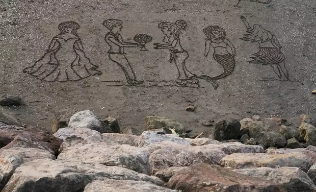 Images are drawn into the sand at the beach of the southern coast of the Caspian Sea outside the port city of Bandar Anzali, Iran, Tuesday, Dec. 23, 2025. (AP Photo/Vahid Salemi)