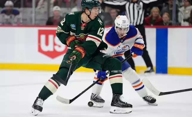 Minnesota Wild left wing Matt Boldy (12) and Edmonton Oilers center Matt Savoie (22) battle for the puck during the first period of an NHL hockey game, Saturday, Dec. 20, 2025, in St. Paul, Minn. (AP Photo/Abbie Parr)
