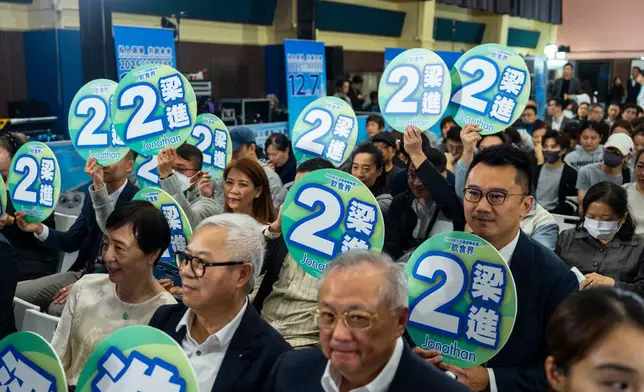 Supporters of Jonathan Leung, candidate of the Legislative Council Catering functional constituency election, hold placard at a forum in Hong Kong on Wednesday, Dec. 3, 2025. (AP Photo/Chan Long Hei)