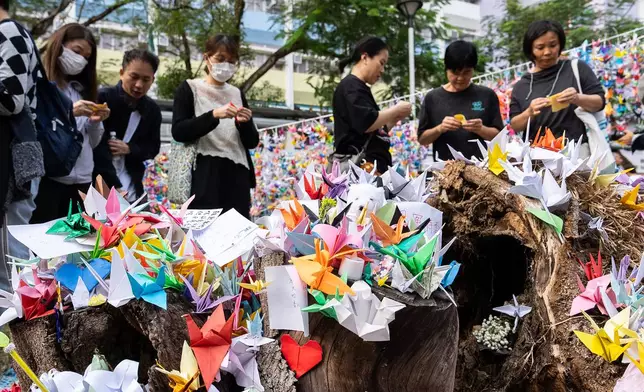 People place paper cranes near the site of the fire at Wang Fuk Court, a residential estate in the Tai Po district of Hong Kong's New Territories on Wednesday, Dec 3, 2025. (AP Photo/Chan Long Hei)