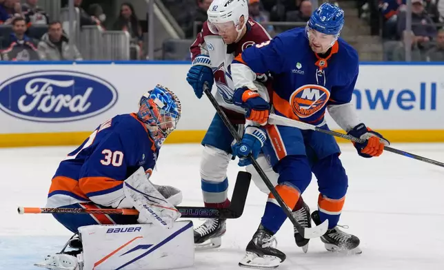 Colorado Avalanche's Gabriel Landeskog, center, and New York Islanders' Adam Pelech, right, watch as goaltender Ilya Sorokin makes a save during the third period of an NHL hockey game, Thursday, Dec. 4, 2025, in Elmont, N.Y. (AP Photo/Seth Wenig)