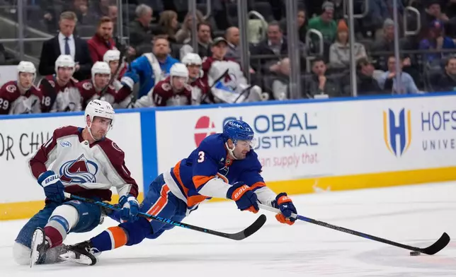 Colorado Avalanche's Brock Nelson, left, and New York Islanders' Adam Pelech dive for the puck during the second period of an NHL hockey game, Thursday, Dec. 4, 2025, in Elmont, N.Y. (AP Photo/Seth Wenig)
