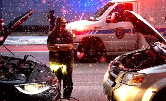 Devon Jordan, of Brainerd , helps a person start their car durning heavy snow fall on Sunday, Dec. 28, 2025 in downtown Minneapolis. (Jerry Holt /Star Tribune via AP)