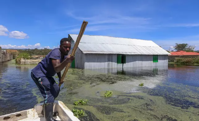 A man paddles a boat next to flooded buildings after Lake Naivasha swelled and inundated homes, displacing hundreds in Kihoto Village in Naivasha, Kenya's Rift Valley region, Tuesday, Nov. 11, 2025. (AP Photo/Andrew Kasuku)