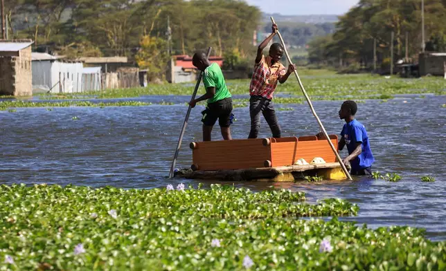 People use a boat to cross floodwaters as residential buildings remain submerged after Lake Naivasha swelled and inundated homes, displacing people in Kihoto Village, in Naivasha, Kenya's Rift Valley region, on Tuesday, Nov. 11, 2025. (AP Photo/Andrew Kasuku)
