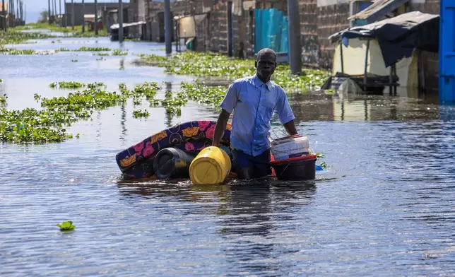 A man salvages his belongings after Lake Naivasha swelled and inundated homes, displacing hundreds in Kihoto Village, in Naivasha, Kenya's Rift Valley region, on Tuesday, Nov. 11, 2025. (AP Photo/Andrew Kasuku)