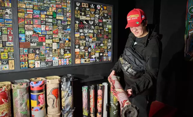 Ukrainian street artist Maxim Kilderov shows rocket tubes and military patches in his private museum that displays a collection of battlefield artifacts documenting Russia's invasion of Ukraine in Kyiv, Ukraine, Friday, Dec. 12, 2025. (AP Photo/Efrem Lukatsky)