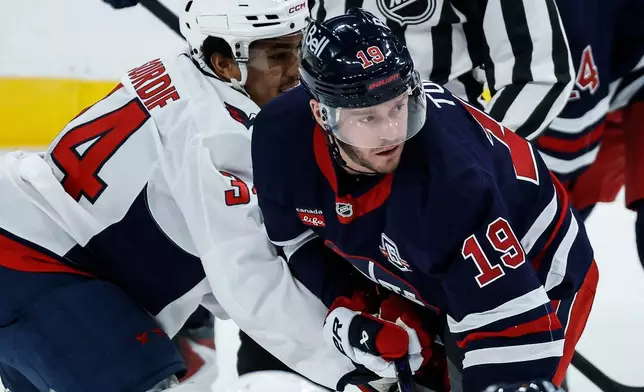 Winnipeg Jets' Jonathan Toews (19) and Washington Capitals' Justin Sourdif (34) battle for position during the first period of an NHL game in Winnipeg on Saturday, Dec. 13, 2025. (John Woods/The Canadian Press via AP)
