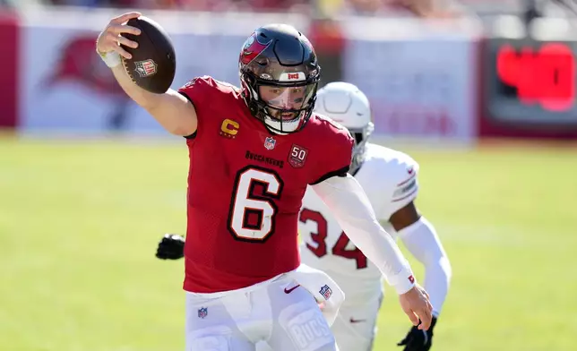 Tampa Bay Buccaneers quarterback Baker Mayfield (6) runs past Arizona Cardinals safety Jalen Thompson (34) during the first half of an NFL football game Sunday, Nov. 30, 2025, in Tampa, Fla. (AP Photo/Chris O'Meara)