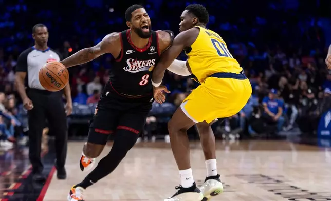 Philadelphia 76ers' Paul George, left, drives to the basket with Indiana Pacers' Bennedict Mathurin, right, defending during the first half of an NBA basketball game, Friday, Dec. 12, 2025, in Philadelphia. (AP Photo/Chris Szagola)
