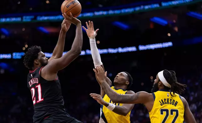 Philadelphia 76ers' Joel Embiid, left, looks to shoot against Indiana Pacers' Bennedict Mathurin, center, and Isaiah Jackson, right, during the first half of an NBA basketball game, Friday, Dec. 12, 2025, in Philadelphia. (AP Photo/Chris Szagola)